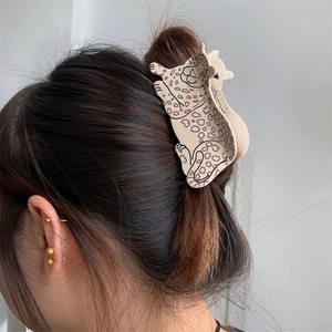 Detail view of a leopard-shaped cellulose acetate hair claw clip styled on a bun