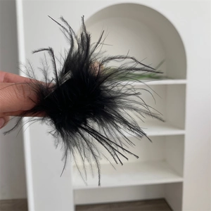 Vue détaillée d'une pince à cheveux en plumes noires sur fond blanc minimaliste et moderne