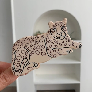 Detailed view of an acetate leopard hair claw clip with black spots on light beige