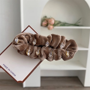 Détail d'un chouchou en velours marron orné de strass brillants de taille marquise