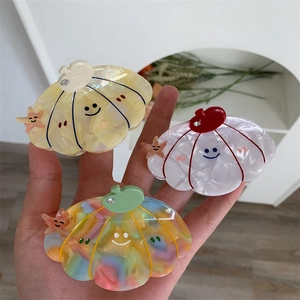 Detailed view of pearlescent acetate hair claws in pumpkin and starfish shapes
