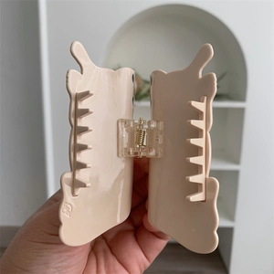 Detail showing high-quality acetate hair claw clip with golden metal spring mechanism