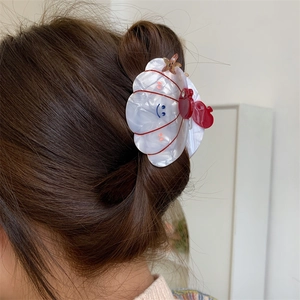 Detail of shell hair claw clip with crab and star accents on brown braided hair