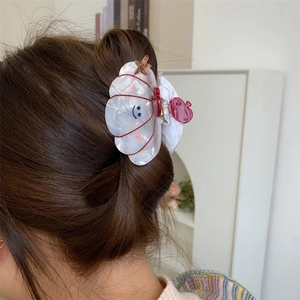 Detail of shell-shaped acetate hair claw with smiling face pattern in hair styling