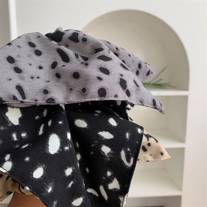 Detail view of retro polka dot chiffon hair scrunchies in grey, black, and beige colors