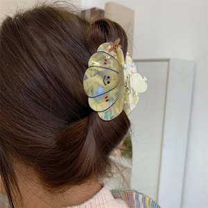 Medium seashell hair claw with pearlescent finish, smiling face and starfish accent