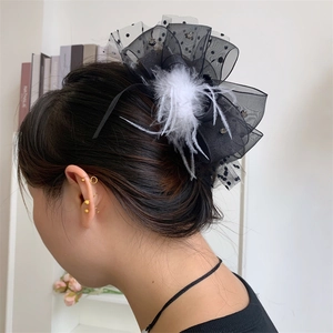 Detail of elegant black polka dot lace hair claw with white feathers and shiny rhinestones