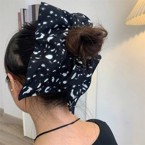 Close-up of retro black and white polka dot bow hair scrunchie on a woman's hair bun