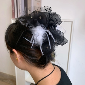 Detail of lace bow hair claw clip with plush feathers and sparkling rhinestones