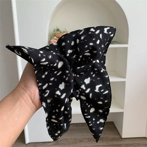 Detail of a large black oversized hair scrunchie with white polka dot pattern design