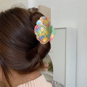 Detail of colorful marble acetate shark hair claw clip worn on dark brown hair