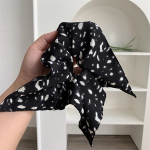 Vintage retro black square hair scrunchie with white polka dots held by a hand
