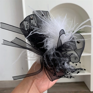 Close-up of lace polka dot ribbon with white feathers and rhinestones on a plush hair claw