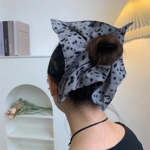 Detailed view of grey polka dot scrunchie styled on a bun with vintage decor