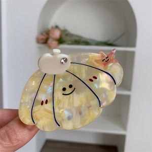 Detailed shot of acetic acid shell-shaped hair claw with star charm and smile pattern