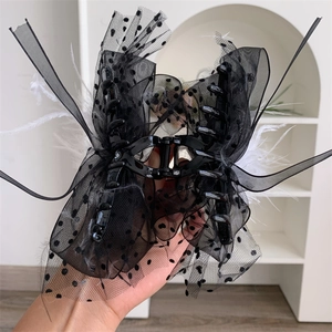 Detail view of large lace bow hair claw clip with polka dots and feathers