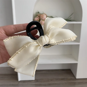 Détail de la pince à cheveux en ruban crème avec bordure délicate en perles nacrées