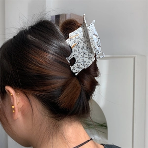 Détail d'une pince à cheveux en acétate à motif léopard blanc portée avec boucles d'oreilles