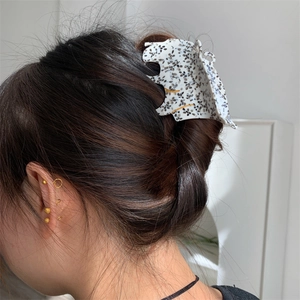 Détail de la pince à cheveux léopard en acétate avec motif floral noir sur blanc