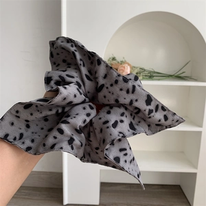 Detail shot of a grey chiffon scrunchie with black polka dots and soft texture