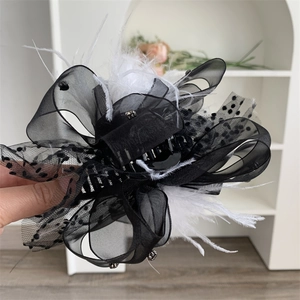 Detail of lace polka dot bow hair claw with feathers and rhinestones for women
