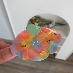 Macro shot of pumpkin-shaped acetate hair claw with smiling face and rhinestone detail