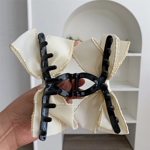 Détail de la grande pince à cheveux avec nœud en maille et bordure en dentelle ondulée