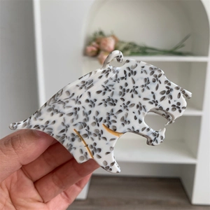 Détail d'une pince à cheveux léopard avec taches noires et blanches et contours dorés