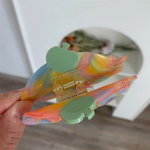 Detail of a medium rainbow acetate hair claw clip featuring a green apple-shaped handle