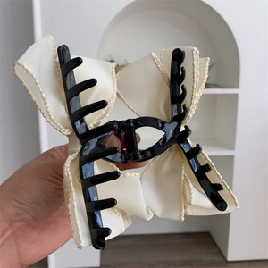 Détail d'élégante pince à cheveux nœud en maille blanche avec ruban à bords ondulés et ressort