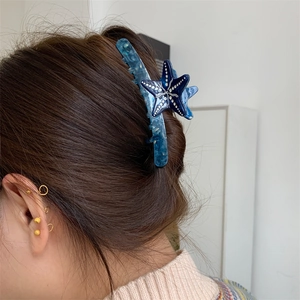 Fermaglio a stella marina in acetato blu sfumato indossato sui capelli lunghi
