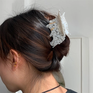 Vue détaillée d'une pince à cheveux chat en acétate marbré blanc portée en chignon