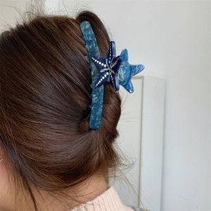 Dettaglio del fermaglio a stella marina in acetato blu marmorizzato su capelli lunghi