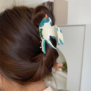 Détail d'une pince à cheveux en acétate en forme d'oiseau portée sur un chignon élégant