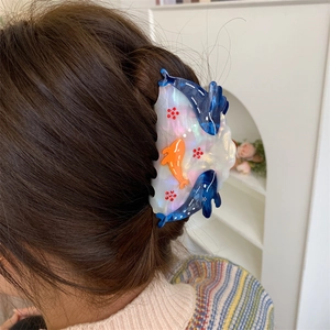 Ocean-themed mother-of-pearl acetate hair claw clip with dolphin motifs in hair