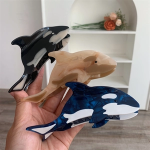 Detailed view of three killer whale hair claws in black, brown, and blue marble acetate