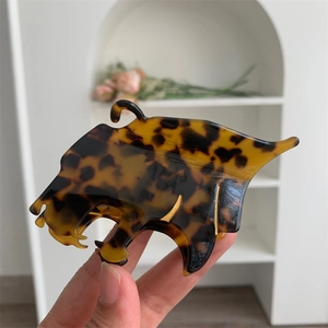 Détail d'une pince à cheveux léopard avec bordure dorée et motif écaille