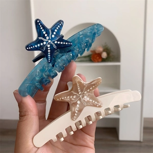 Dettaglio di fermagli per capelli a stella marina in acetato blu e bianco crema