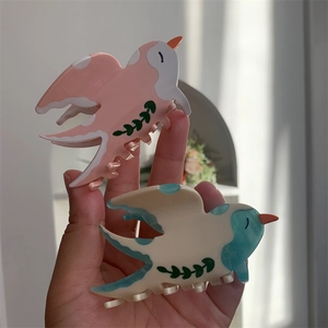 Détail des pinces à cheveux en acétate en forme d'oiseau, tons rose et bleu fleuri