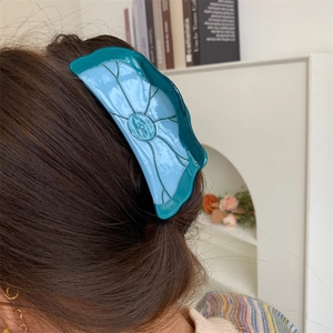 Détail d'une pince à cheveux bicolore en acétate sur cheveux longs dans un cadre cozy