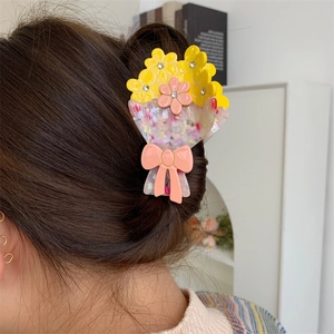 Dettaglio molletta per capelli a fiori in acetato con strass e fiocco rosa indossata
