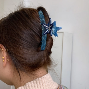 Dettaglio di un fermaglio per capelli a stella marina blu in acetato su capelli lunghi