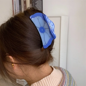 Détail de la pince à cheveux lotus en acétate bleu montrant la texture sur un chignon