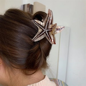 Détail de la pince à cheveux en forme d'étoile de mer sur cheveux bruns foncés