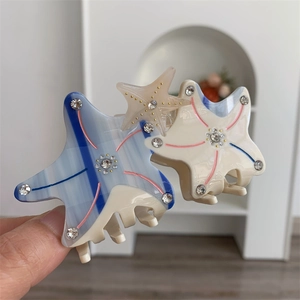 Detailed view of starfish hair claw clips in blue and beige with sparkling rhinestones