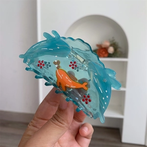 Detail of blue acetate hair claw clip featuring rhinestones and ocean whale design