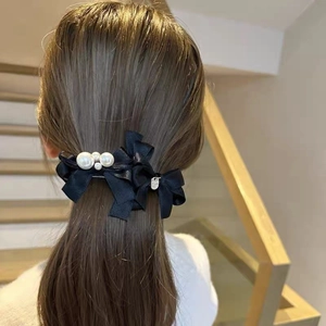 Detail of elegant black layered satin bow hair clip with white pearls and silver pendant