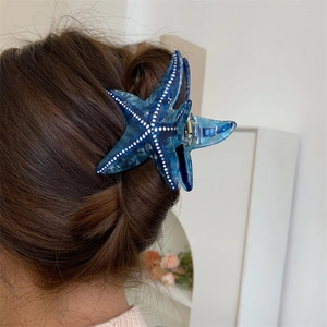 Pince à cheveux étoile de mer en acétate bleu marbré avec pois blancs sur un modèle