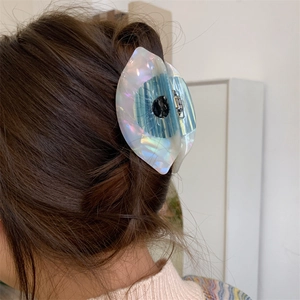Pince à cheveux œil en acétate unique montrée en détail sur une coiffure tressée