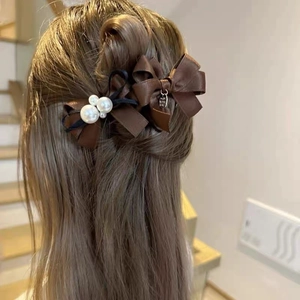 Detailed view of brown satin bow hair clips with pearls and metal tag on model